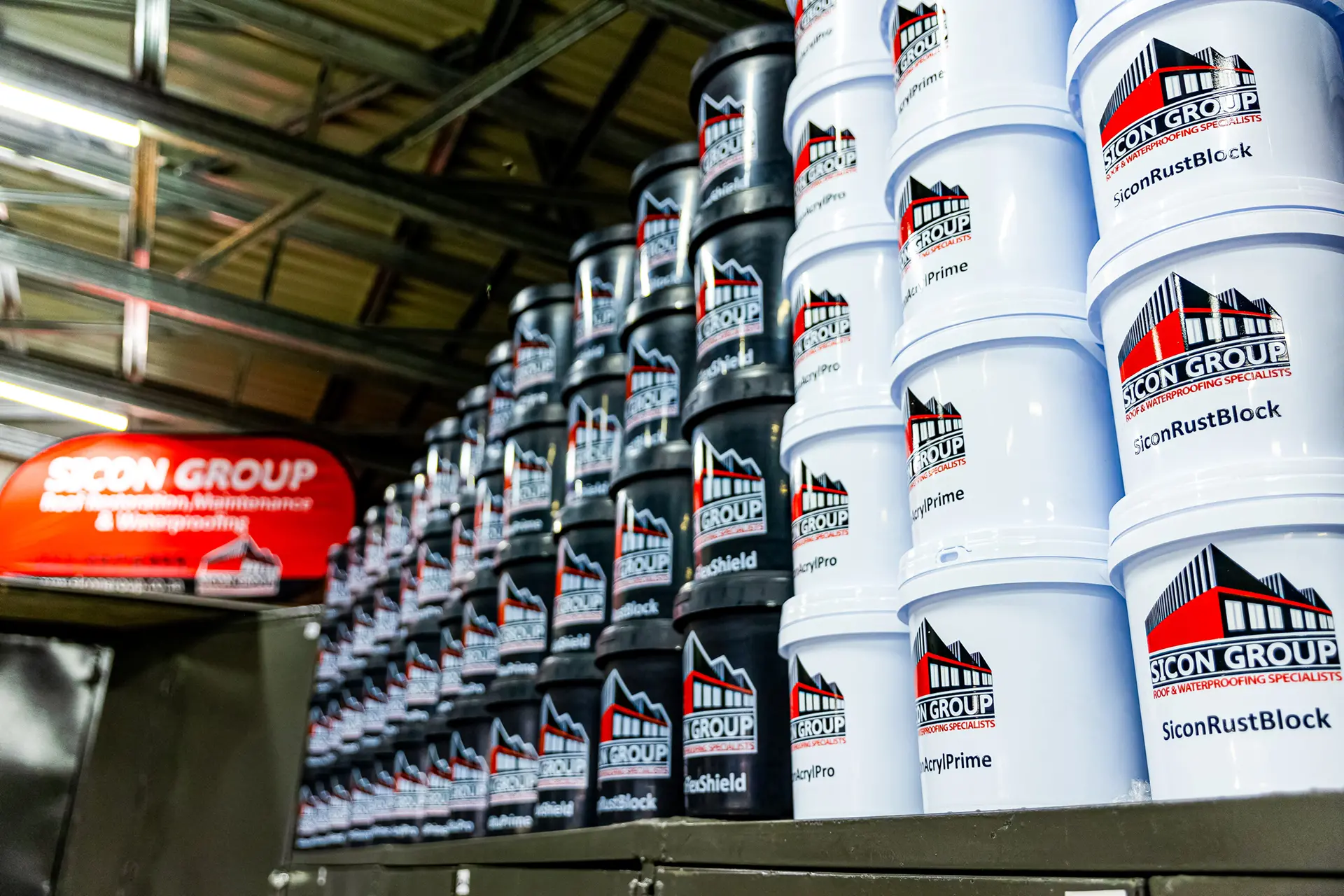 Stacked Sicon Group buckets of roof waterproofing products in a warehouse, vital for affordable roof repair near me projects.